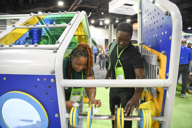 Two attendees look at playground set ups