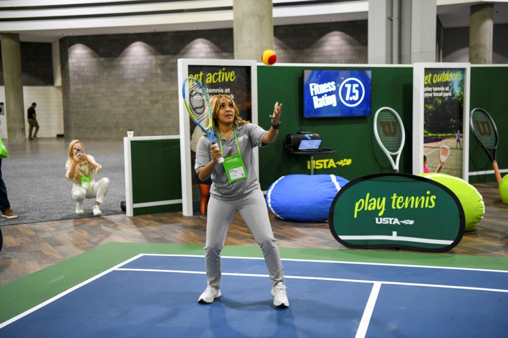 Conference attendee plays tennis in exhibit hall