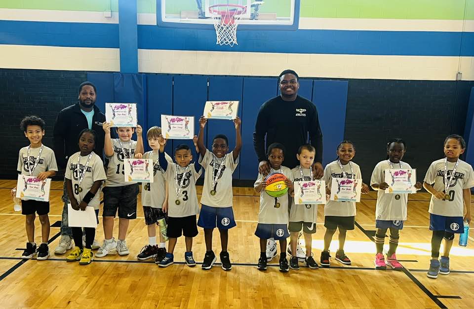 Young kids wear medals and hold their awards in air while posing with coaches. Photo courtesy of City of Fort Worth Park and Recreation Department.